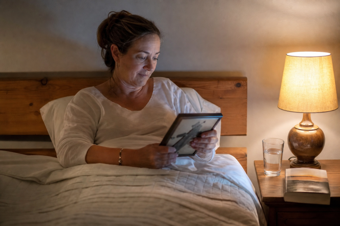 Signs spirits are contacting you: a woman with an old photograph at night Woman in her fifties sitting up in bed at night with the bedside lamp on, looking at an old framed photo in her hands