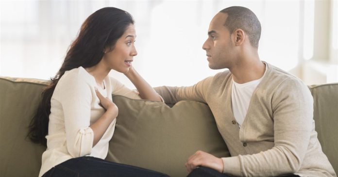 Two people talking face to face while seated on a sofa.
