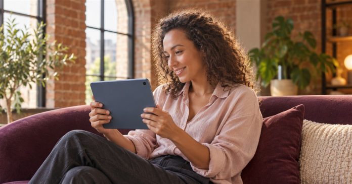Spiritual connection personal conversation A curly-haired woman holding a blue tablet while smiling during a conversation.