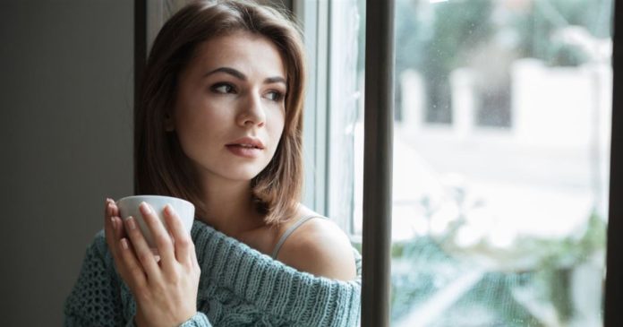 Three types empathy reflection A woman in a teal sweater holding a cup and looking through a window.